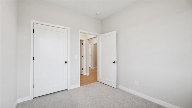 unfurnished bedroom with light colored carpet and a closet