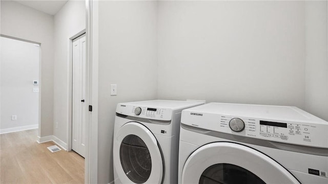 laundry room with washer and dryer and light hardwood / wood-style flooring