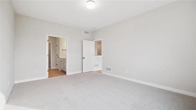 unfurnished bedroom with light colored carpet and ensuite bath