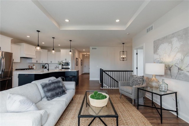 living room featuring a raised ceiling, dark hardwood / wood-style flooring, and sink