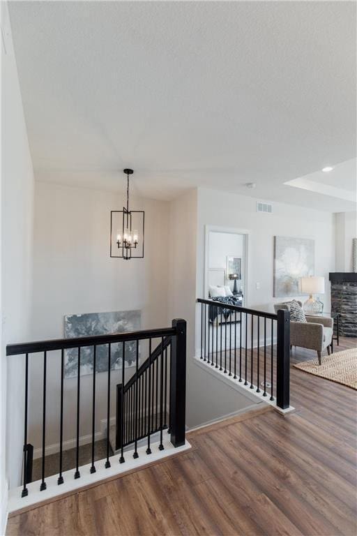 stairs with wood-type flooring and a notable chandelier