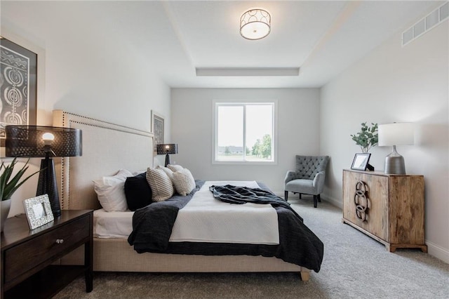 bedroom featuring a tray ceiling and carpet