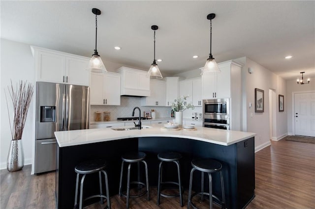 kitchen featuring stainless steel appliances, white cabinetry, and a kitchen island with sink