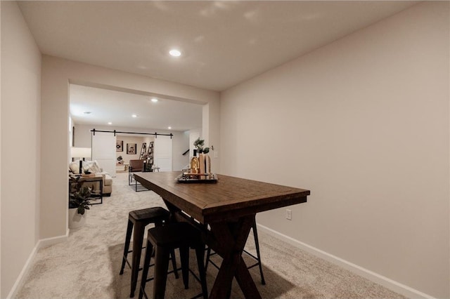 dining room featuring light carpet and a barn door