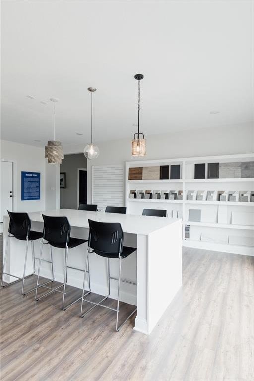 kitchen with a breakfast bar, a kitchen island, light hardwood / wood-style floors, and decorative light fixtures