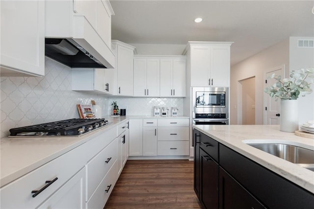 kitchen with backsplash, white cabinetry, dark wood-type flooring, and stainless steel appliances