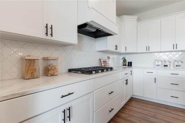 kitchen featuring light stone counters, tasteful backsplash, dark hardwood / wood-style flooring, white cabinetry, and stainless steel gas cooktop