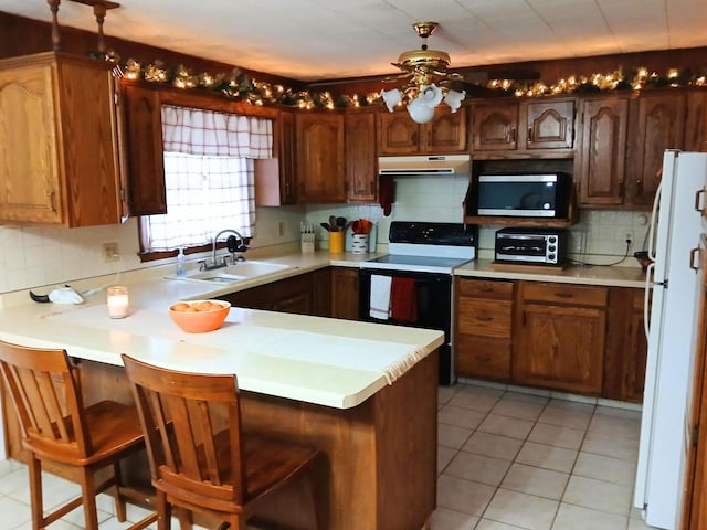 kitchen featuring white appliances, kitchen peninsula, tasteful backsplash, a kitchen breakfast bar, and sink