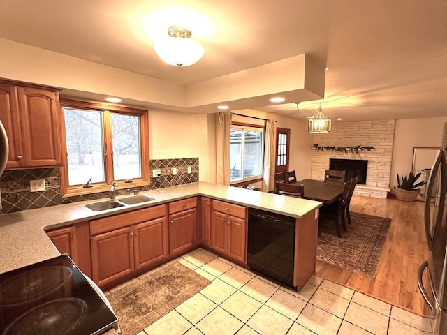 kitchen with kitchen peninsula, stainless steel fridge, sink, dishwasher, and plenty of natural light