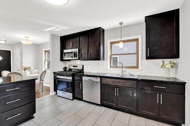 kitchen featuring hanging light fixtures, sink, decorative backsplash, appliances with stainless steel finishes, and dark brown cabinetry