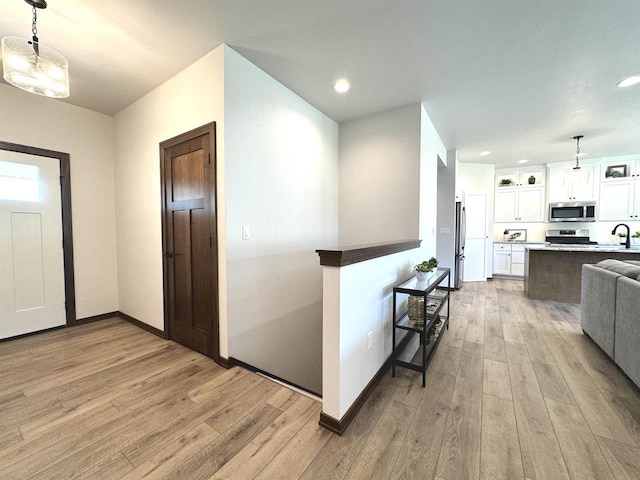 kitchen with sink, light hardwood / wood-style floors, pendant lighting, white cabinets, and appliances with stainless steel finishes