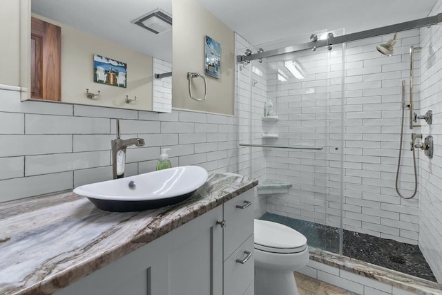 bathroom with vanity, backsplash, toilet, tile walls, and an enclosed shower