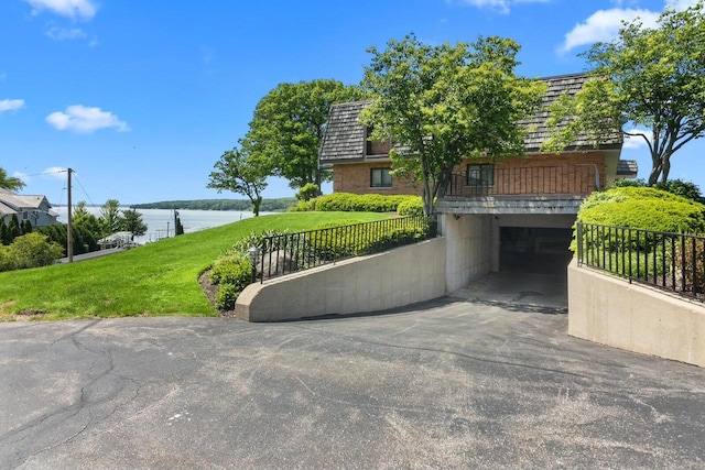 view of front facade with a garage, a water view, and a front yard