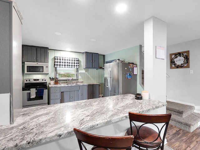 kitchen featuring gray cabinetry, sink, dark wood-type flooring, tasteful backsplash, and appliances with stainless steel finishes