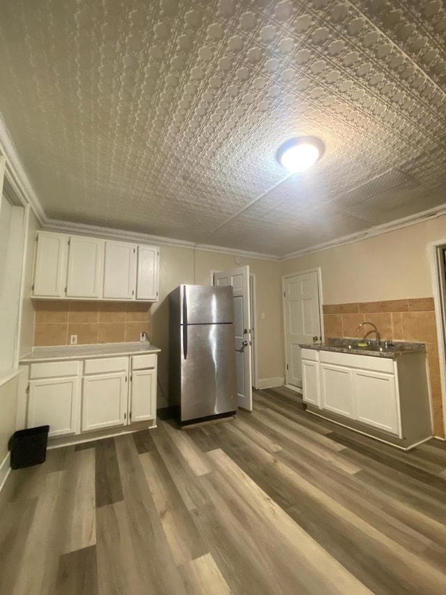 kitchen featuring stainless steel fridge, dark hardwood / wood-style floors, white cabinetry, and sink