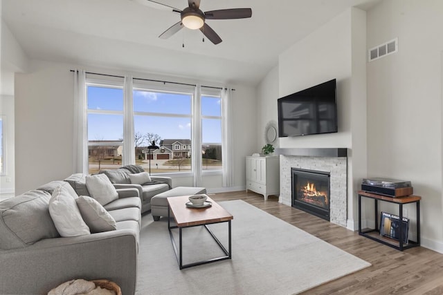 living room featuring a fireplace, wood-type flooring, ceiling fan, and lofted ceiling