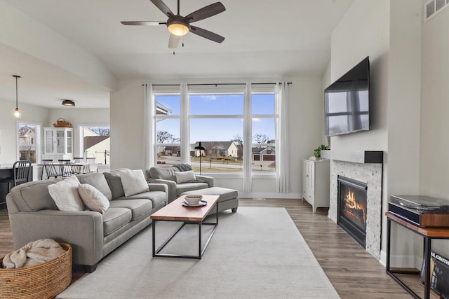 living room featuring ceiling fan, wood-type flooring, plenty of natural light, and a fireplace