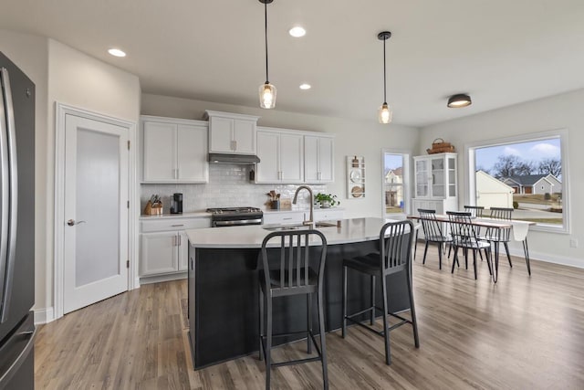 kitchen featuring white cabinetry, sink, hanging light fixtures, a center island with sink, and appliances with stainless steel finishes