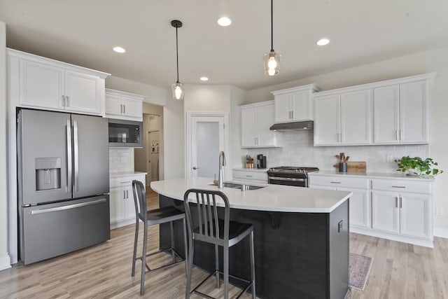 kitchen featuring pendant lighting, white cabinets, a center island with sink, decorative backsplash, and appliances with stainless steel finishes