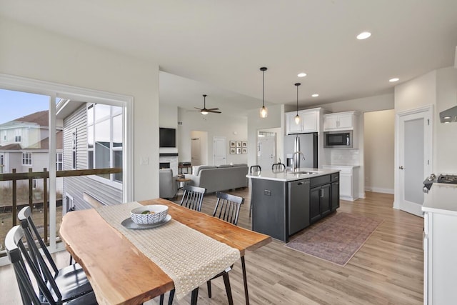 dining area with ceiling fan, sink, and light wood-type flooring