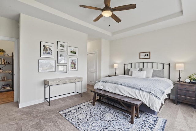 bedroom with light carpet, a raised ceiling, and ceiling fan