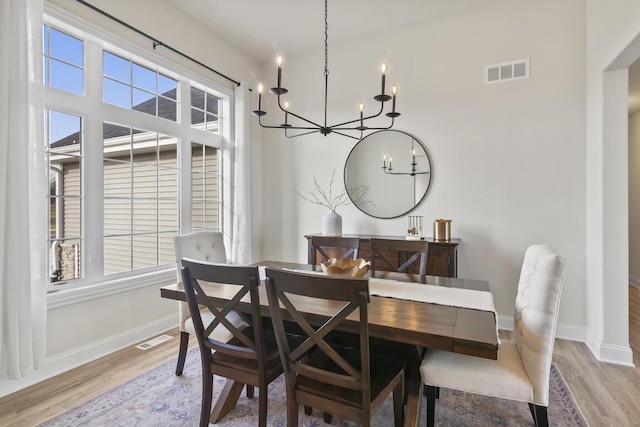 dining room with light hardwood / wood-style floors and a notable chandelier