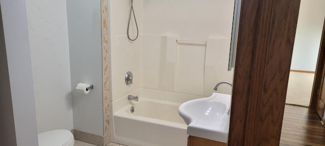 bathroom featuring  shower combination, hardwood / wood-style flooring, and toilet