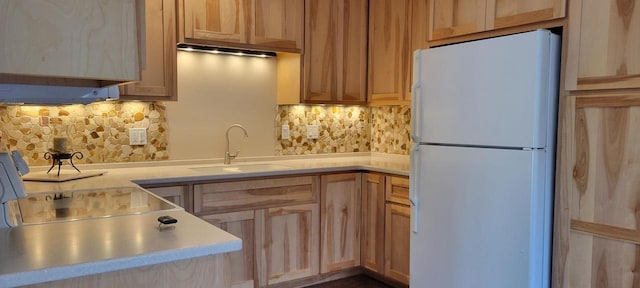 kitchen with white fridge, sink, backsplash, and light brown cabinetry