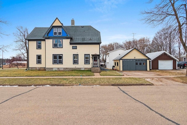 view of front of home with a front yard, an outdoor structure, and a garage