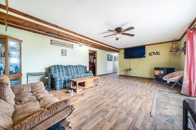 living room with a wood stove, ceiling fan, hardwood / wood-style floors, and crown molding