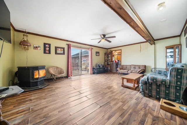 living room featuring hardwood / wood-style flooring, a wood stove, ceiling fan, and ornamental molding