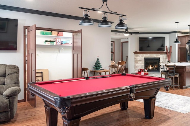 playroom featuring light hardwood / wood-style floors, a stone fireplace, ornamental molding, and pool table