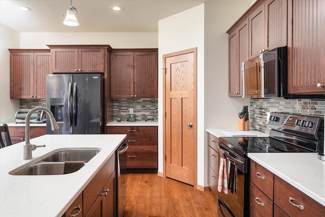 kitchen with sink, pendant lighting, decorative backsplash, appliances with stainless steel finishes, and light wood-type flooring