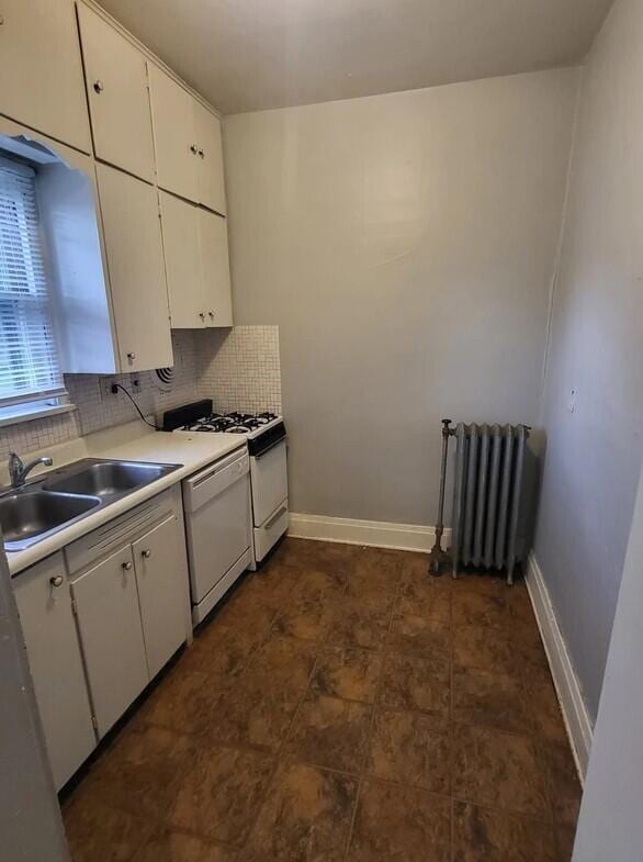 kitchen with white dishwasher, white cabinetry, and radiator heating unit