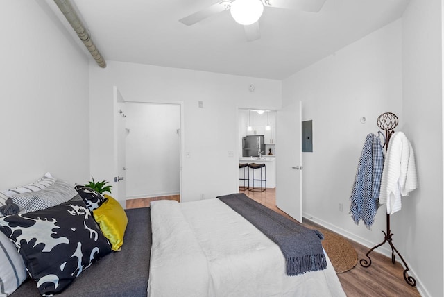 bedroom featuring ceiling fan, electric panel, wood-type flooring, and stainless steel refrigerator