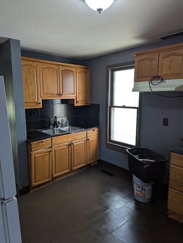 kitchen with tasteful backsplash, extractor fan, stainless steel refrigerator, and sink