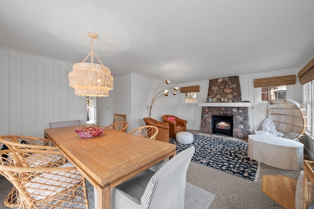 carpeted dining space with a fireplace and a chandelier