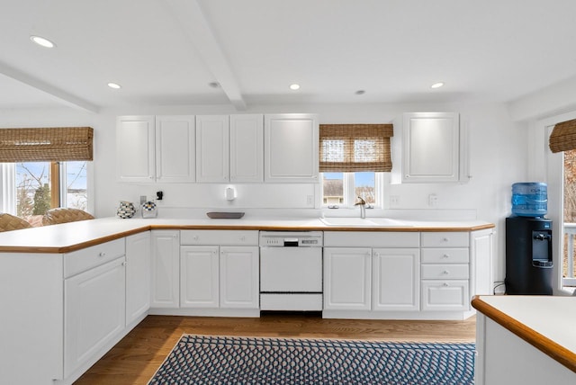 kitchen featuring beam ceiling, white cabinetry, dishwasher, sink, and kitchen peninsula