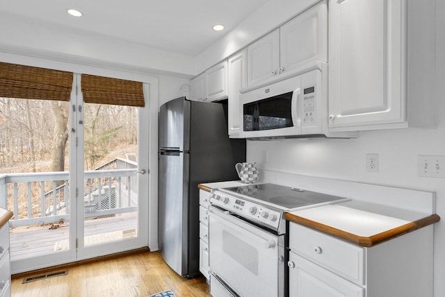 kitchen with a wealth of natural light, white cabinetry, light hardwood / wood-style floors, and white appliances