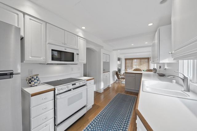 kitchen featuring white appliances, hardwood / wood-style flooring, white cabinetry, and sink