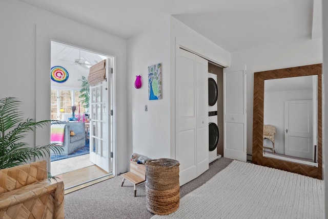 laundry room featuring ceiling fan, carpet, and stacked washer and clothes dryer