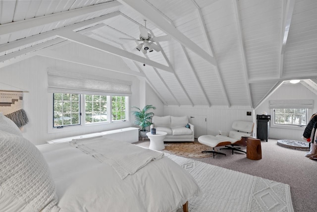 carpeted bedroom with wood walls, vaulted ceiling with beams, and ceiling fan