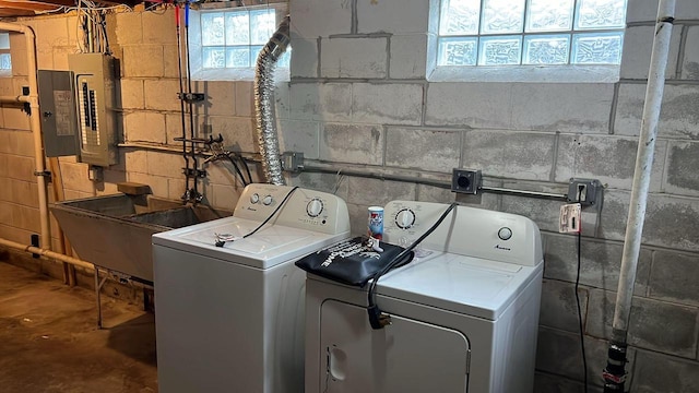 washroom featuring separate washer and dryer, electric panel, and sink