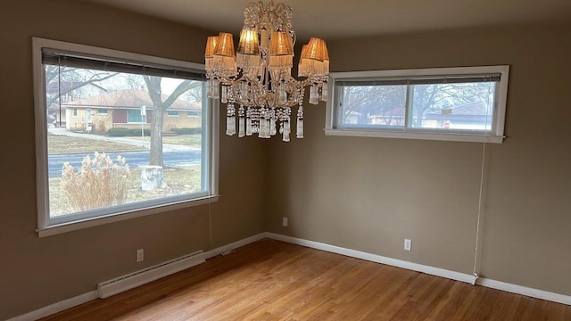 unfurnished dining area with wood-type flooring, an inviting chandelier, and baseboard heating