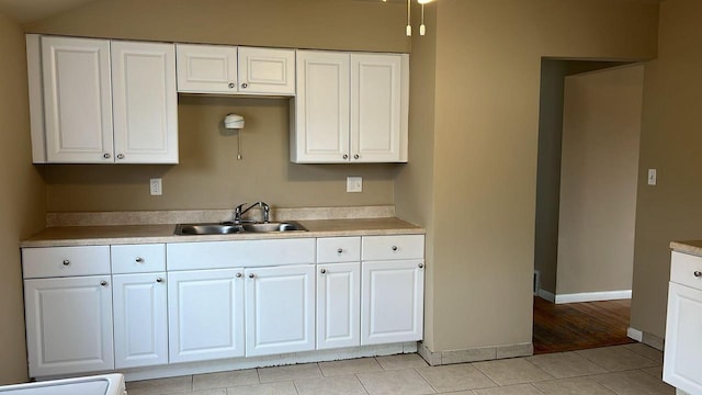 kitchen with white cabinets, light tile patterned floors, and sink