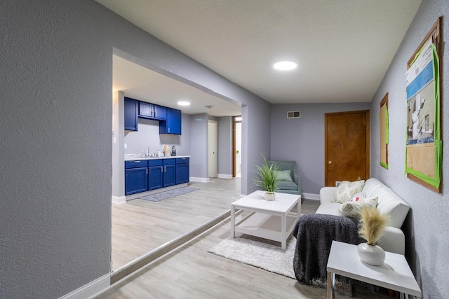 living room with light wood-type flooring, sink, and vaulted ceiling