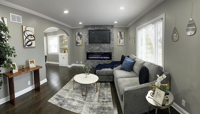 living room featuring dark hardwood / wood-style floors, a stone fireplace, and crown molding