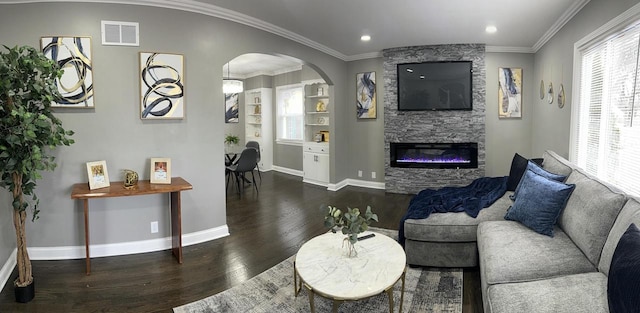 living room with dark hardwood / wood-style floors, a stone fireplace, and crown molding