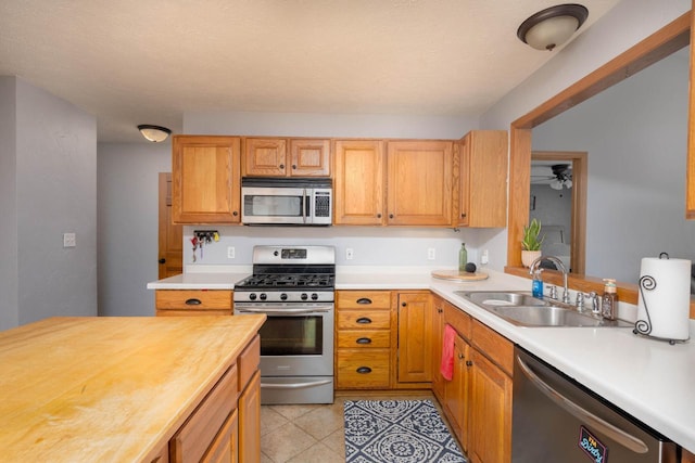 kitchen featuring stainless steel appliances, ceiling fan, sink, light tile patterned floors, and butcher block counters