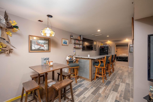 dining area featuring dark hardwood / wood-style flooring and bar area